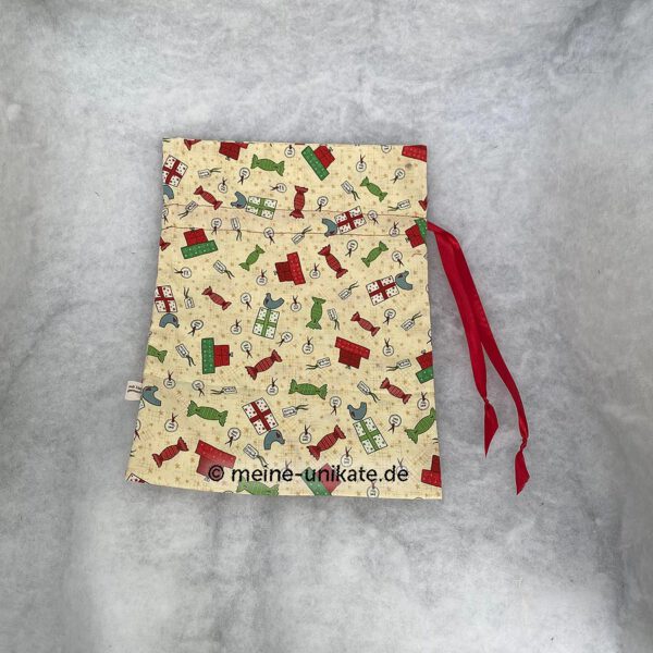 Stoffbeutel, Geschenksack in creme mit Weihnachtsmotiven und roter satinschleife. genäht aus Baumwollstoff, ungefüttert. Stoff-Unikat handmade in Germany