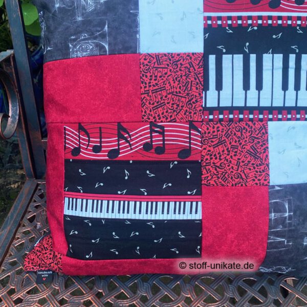 Detailansicht vom Künstlerkissen "Klavierspiel" mit Abbildung von Noten und Klaviertasten. Stoff-Unikat handmade in Deutschland
