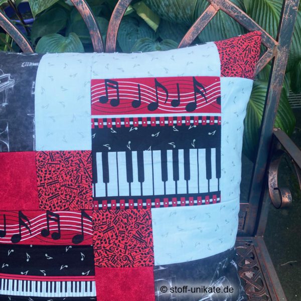Detailansicht vom Künstlerkissen "Klavierspiel" mit Abbildung von Noten und Klaviertasten in schwarz-weiß-rot. Stoff-Unikate handmade in Germany