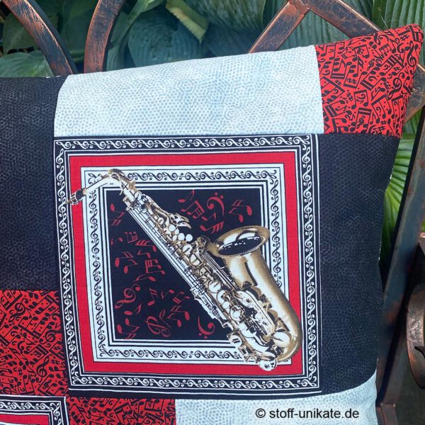 Detailansicht mit Abbildung eines Saxophones mit Notenschlüsseln in schwarz-weiß-rot. Stoff-Unikat handmade in Germany